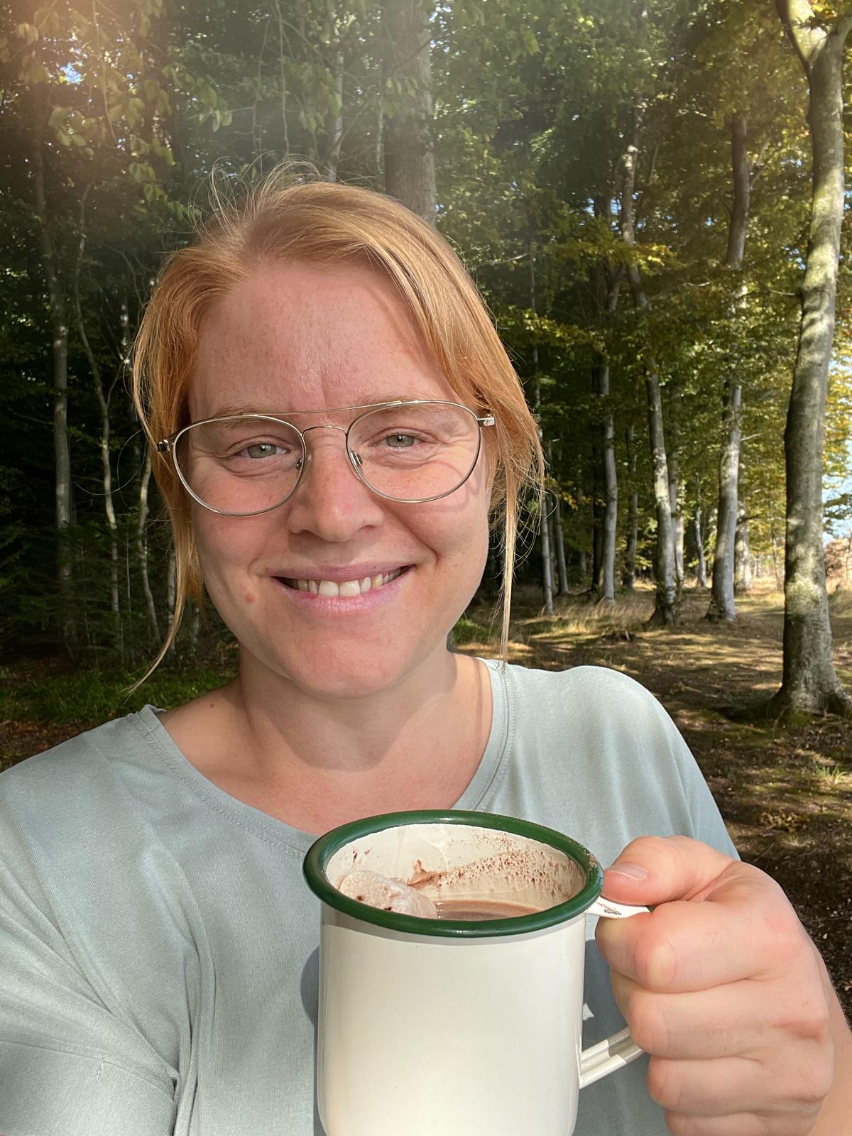 Grundlægger af Elouvia i skoven med en varm kop kakao